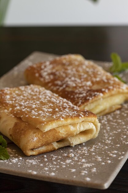 Colpo verticale del primo piano dei rotoli del pancake con zucchero a velo