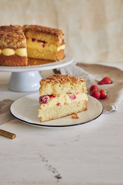 Colpo verticale del primo piano della deliziosa torta alla crema alla vaniglia con fragole all'interno su un tavolo bianco