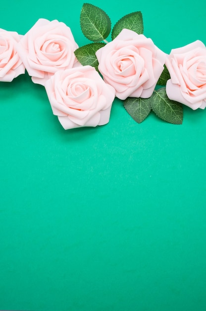 Colpo verticale del primo piano delle rose rosa isolate su una priorità bassa verde con lo spazio della copia