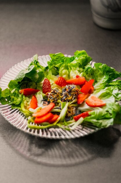 Colpo verticale del primo piano di un piatto vegetariano con le fragole dell'annuncio della lattuga