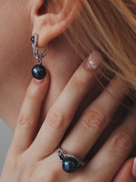Colpo verticale del primo piano di una donna che indossa un anello e orecchini con un ciondolo nero