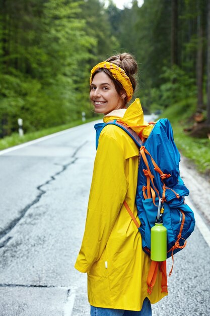 Colpo verticale del turista femminile gode di passeggiare nella foresta verde