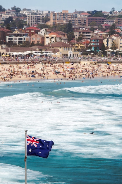 Colpo verticale della bandiera australiana al mare in un'affollata spiaggia di Bondi