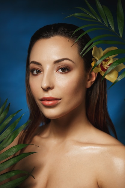 Colpo verticale di bella donna sorridente con il fiore in capelli.