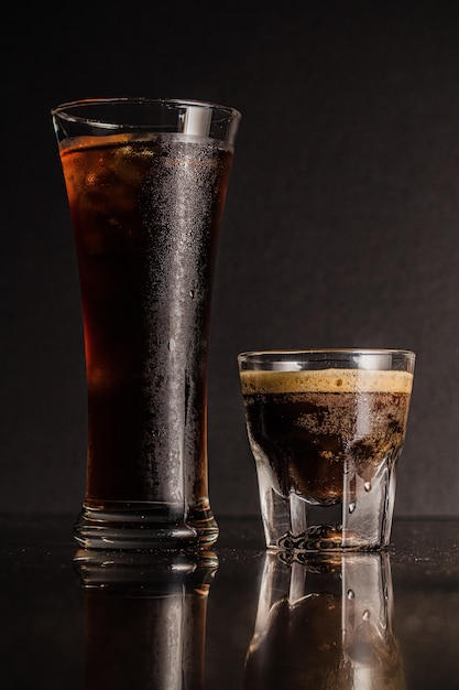 Colpo verticale di bicchieri di liquore e caffè con riflessi