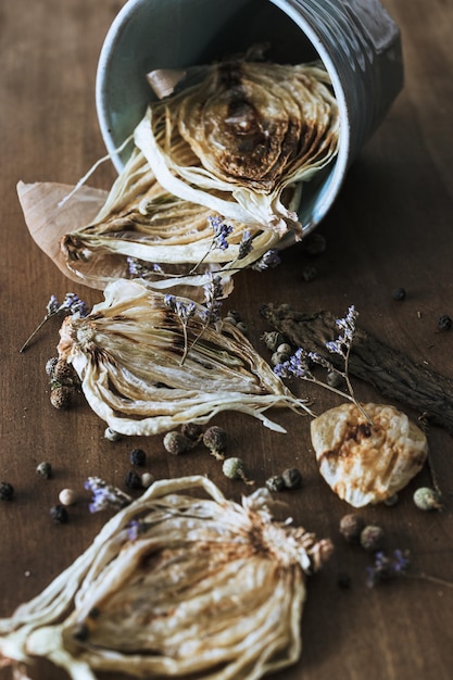 Colpo verticale di cipolle essiccate in una tazza metallica, erbe di incenso e spezie sul tavolo