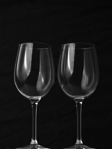 Colpo verticale di due bicchieri di vino vuoti su sfondo nero