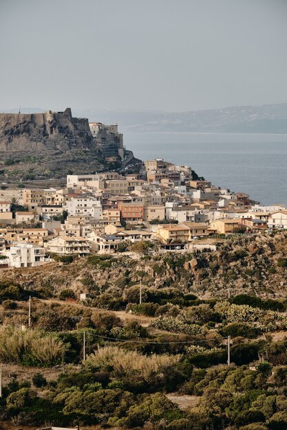 Colpo verticale di edifici sulla collina vicino al mare sotto un cielo blu di giorno