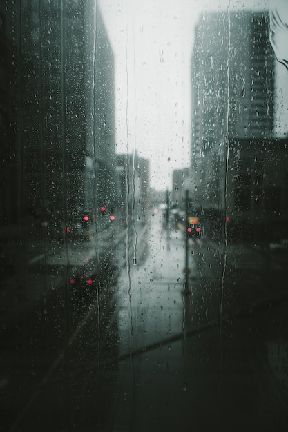 Colpo verticale di gocce di pioggia che piove a dirotto una finestra di vetro