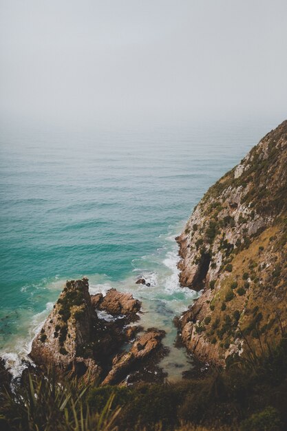 Colpo verticale di grandi rocce a Nugget Point Ahuriri, Nuova Zelanda con uno sfondo nebbioso