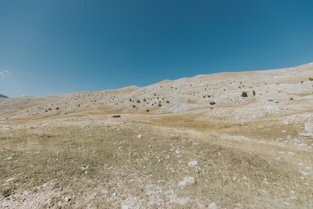 Colpo verticale di montagne e colline con molte rocce sotto il bel cielo blu