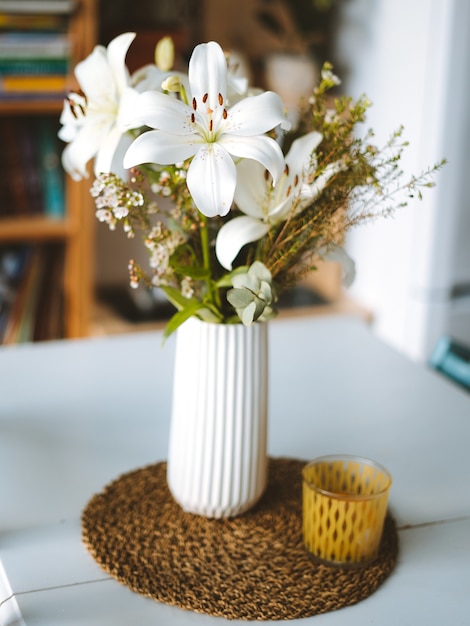 Colpo verticale di orchidee bianche in un vaso su un tavolo all'interno di una stanza a Madeira, Portogallo