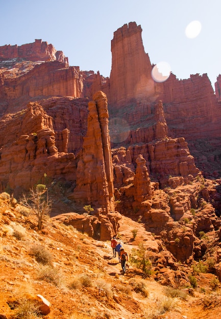 Colpo verticale di persone che camminano su per la collina vicino a una scogliera nel deserto durante il giorno