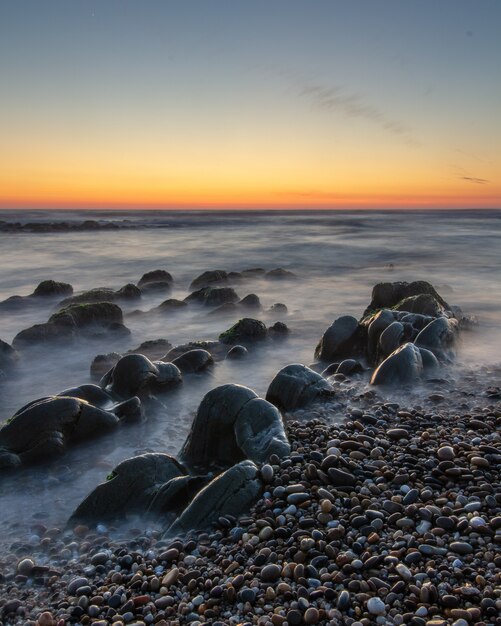 Colpo verticale di un bel tramonto in una spiaggia rocciosa