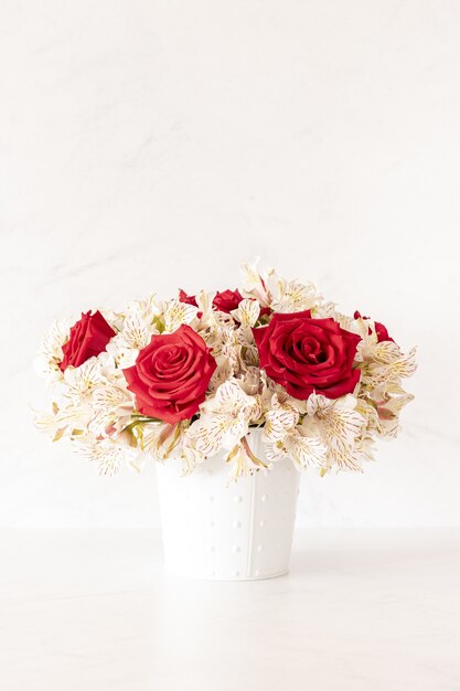 Colpo verticale di un bellissimo bouquet con rose rosse e fiori di giglio in una scatola