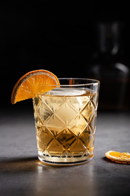 Colpo verticale di un bicchiere di whisky decorato con una fetta di arancia essiccata