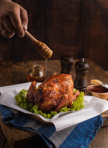 Colpo verticale di un delizioso pollo arrosto guarnito con verdure e miele su un tavolo