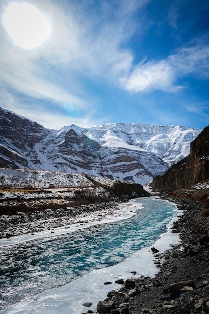 Colpo verticale di un fiume ghiacciato con montagne innevate sullo sfondo