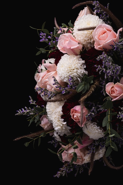 Colpo verticale di un lussuoso bouquet di rose rosa e rosse e dalie bianche su sfondo nero