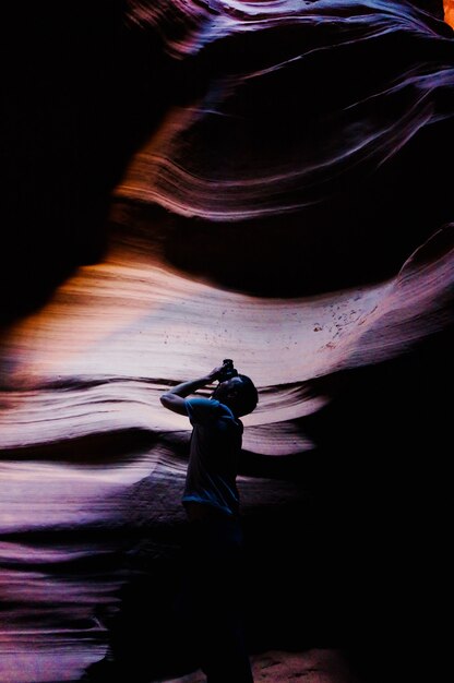 Colpo verticale di un maschio con una macchina fotografica in una grotta che scatta una foto