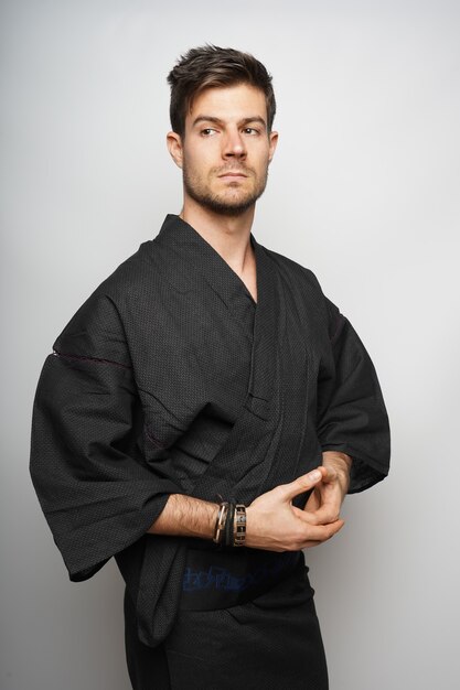Colpo verticale di un maschio in piedi concentrato con il suo kimono in stile giapponese