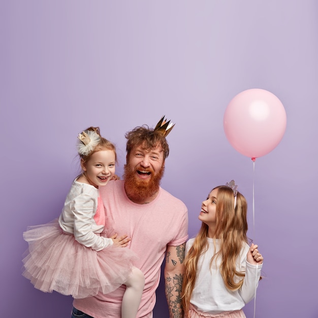 Colpo verticale di un padre single gioioso e ipermotivo e due figlie, celebrare la festa del papà, indossare abiti festivi