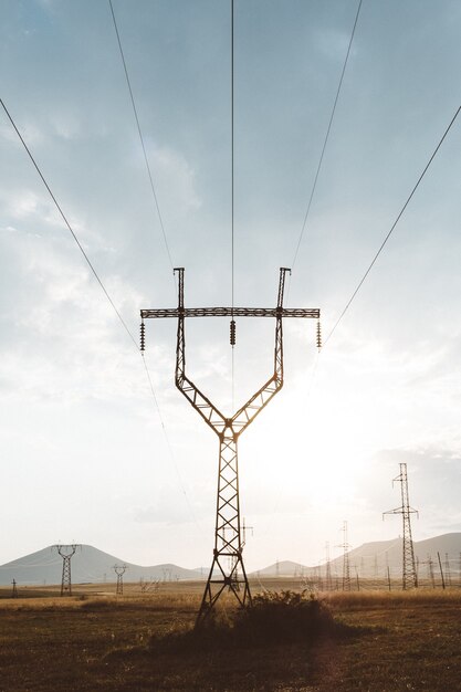 Colpo verticale di un palo elettrico con ringhiere metalliche in cima sotto un cielo nuvoloso