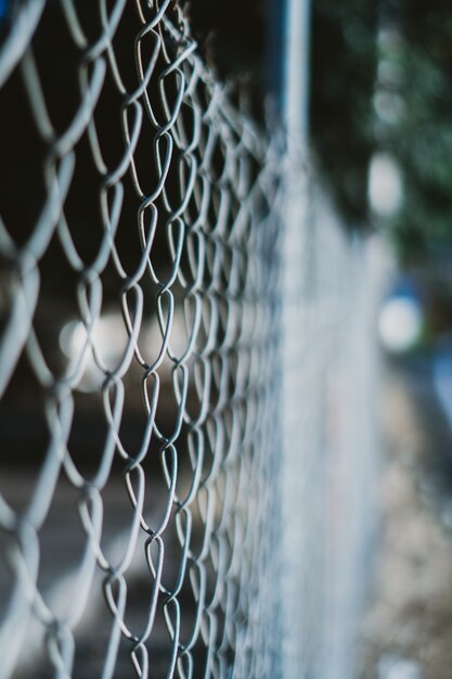 Colpo verticale di un recinto di filo metallico con uno sfondo sfocato