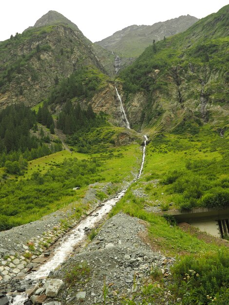 Colpo verticale di un ruscello che scorre acqua con montagne verdi