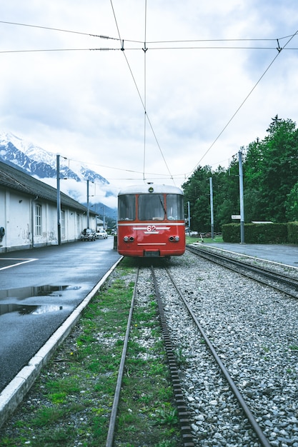 Colpo verticale di un tram rosso che si muove in avanti attraverso le rotaie