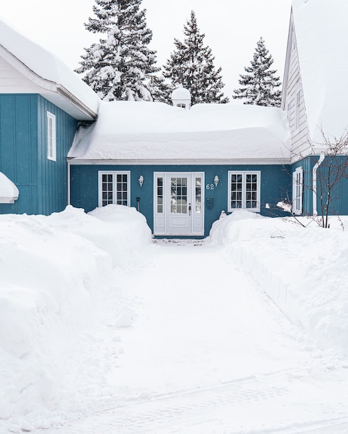 Colpo verticale di una casa blu ricoperta di neve bianca durante l'inverno