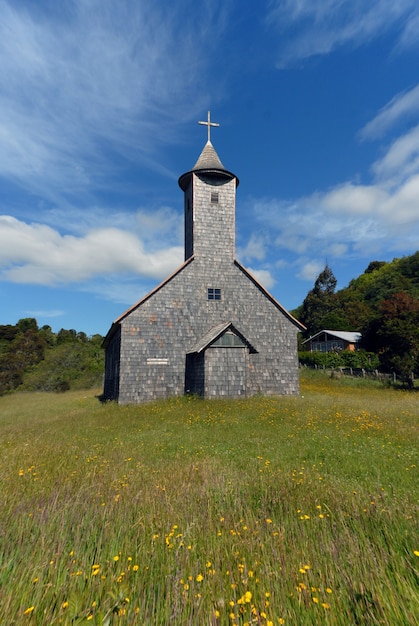Colpo verticale di una chiesa in un campo erboso sotto un cielo blu