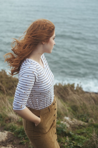 Colpo verticale di una donna in piedi sulla riva con il mare