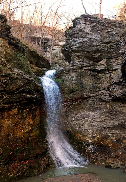 Colpo verticale di una potente cascata che scorre attraverso le rocce in una foresta