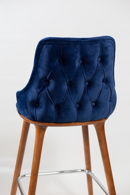 Colpo verticale di una sedia blu con pulsanti dietro uno sfondo bianco