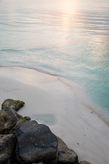 Colpo verticale di una spiaggia sabbiosa con il riflesso del sole nell'acqua blu