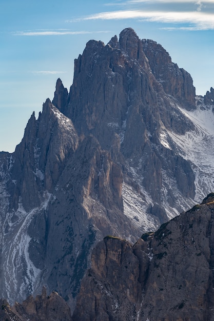 Colpo verticale di una splendida vetta di una roccia nelle Alpi italiane sotto il cielo nuvoloso al tramonto