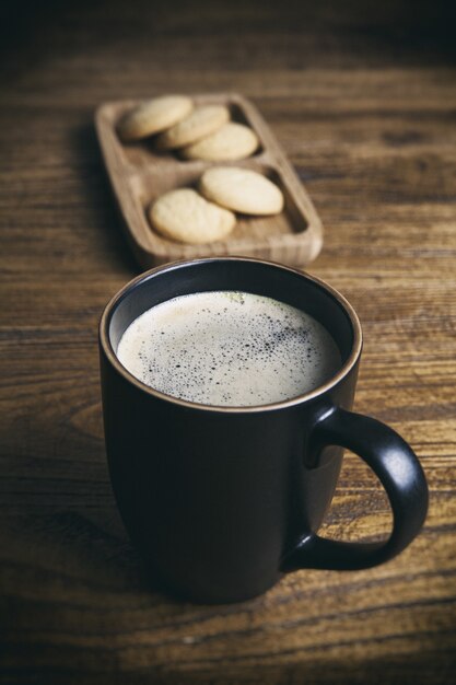 Colpo verticale di una tazza di caffè nero e biscotti