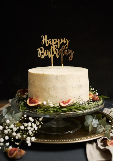 Colpo verticale di una torta di sogno bianco buon compleanno con foglie verdi nella parte inferiore