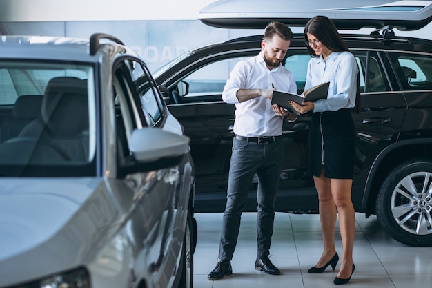 Commesso e donna che cercano un&#39;auto in uno showroom di automobili