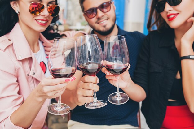 Compagnia di giovani hipster di amici seduti in caffè sulla strada della città