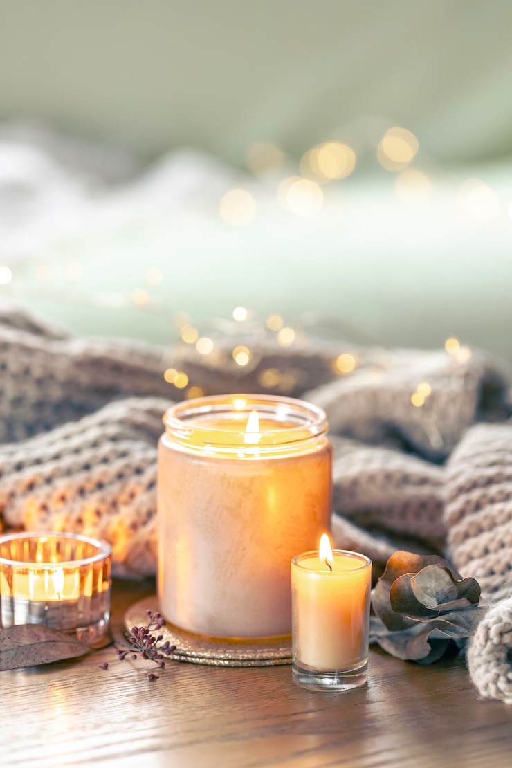 Foto gratuito composizione accogliente con candele e un elemento a maglia su uno sfondo sfocato
