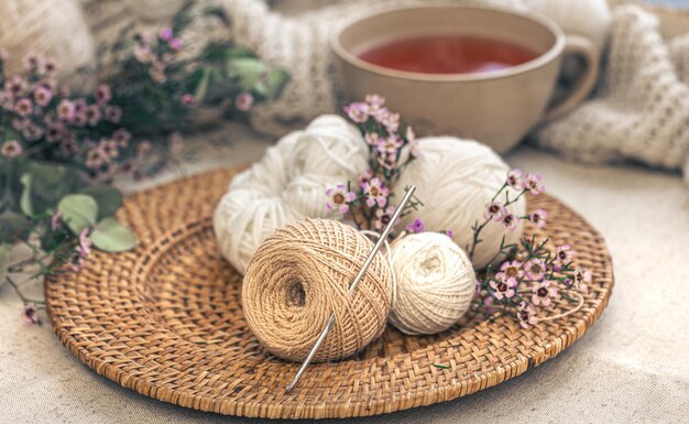 Composizione accogliente con fili per maglieria una tazza di tè e fiori