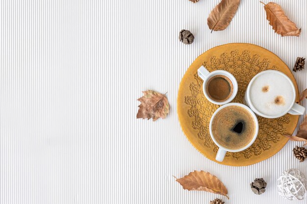 Composizione autunnale con tazze di caffè e foglie su sfondo bianco