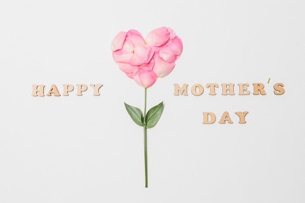 Composizione del titolo di giorno di madri felice vicino alla fioritura rosa a forma di cuore
