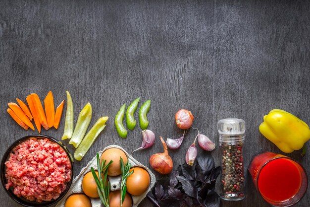 Composizione di carne cruda con verdure e spezie su fondo di legno