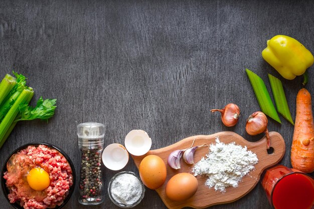 Composizione di carne cruda con verdure e spezie su fondo di legno