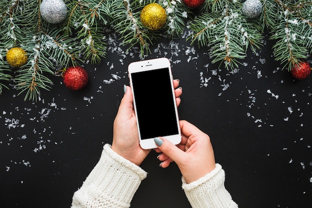 Composizione di Natale con le mani che tengono smartphone