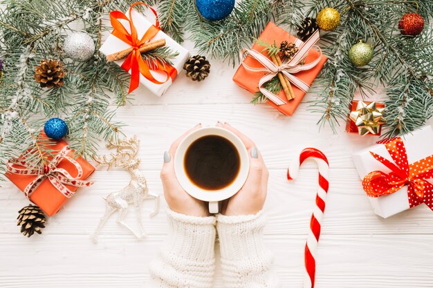 Composizione di Natale con le mani intorno a tazza di caffè