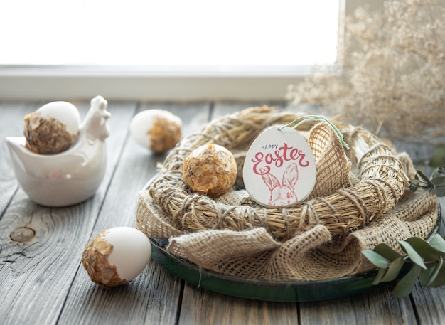 Composizione di Pasqua con uova di Pasqua decorate e nido decorativo su una superficie di legno